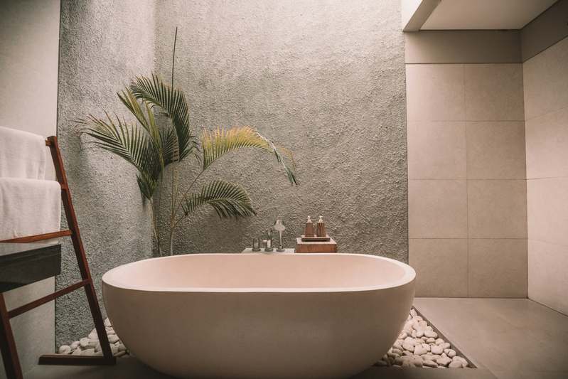 Diverse group of home improvement bloggers reviewing bathtub models in a well-lit studio with ceramic tile backdrop and matte-finish tubs